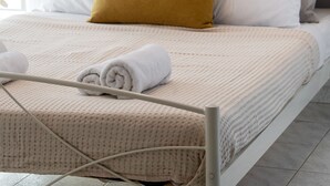 A neatly made bed with a patterned bedspread, a single mustard-colored pillow, and a white pillow. - George House (Lefkada)