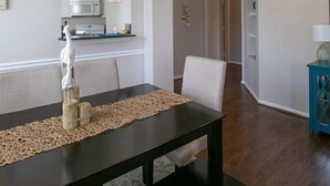 A dining area with a black table, beige chairs, and a woven placemat. - Legacy Villa 1901 | Just a Short Walk to the Beach! (Gulfport)