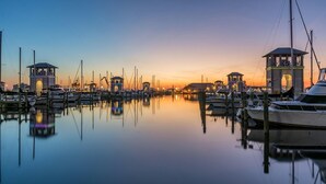 A marina at dusk with boats docked, calm water, and illuminated structures.