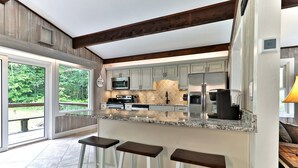 A kitchen with a large island, bar stools, and a view of the outdoors. - Breakaway House by Killington Vacation Rentals (Killington)