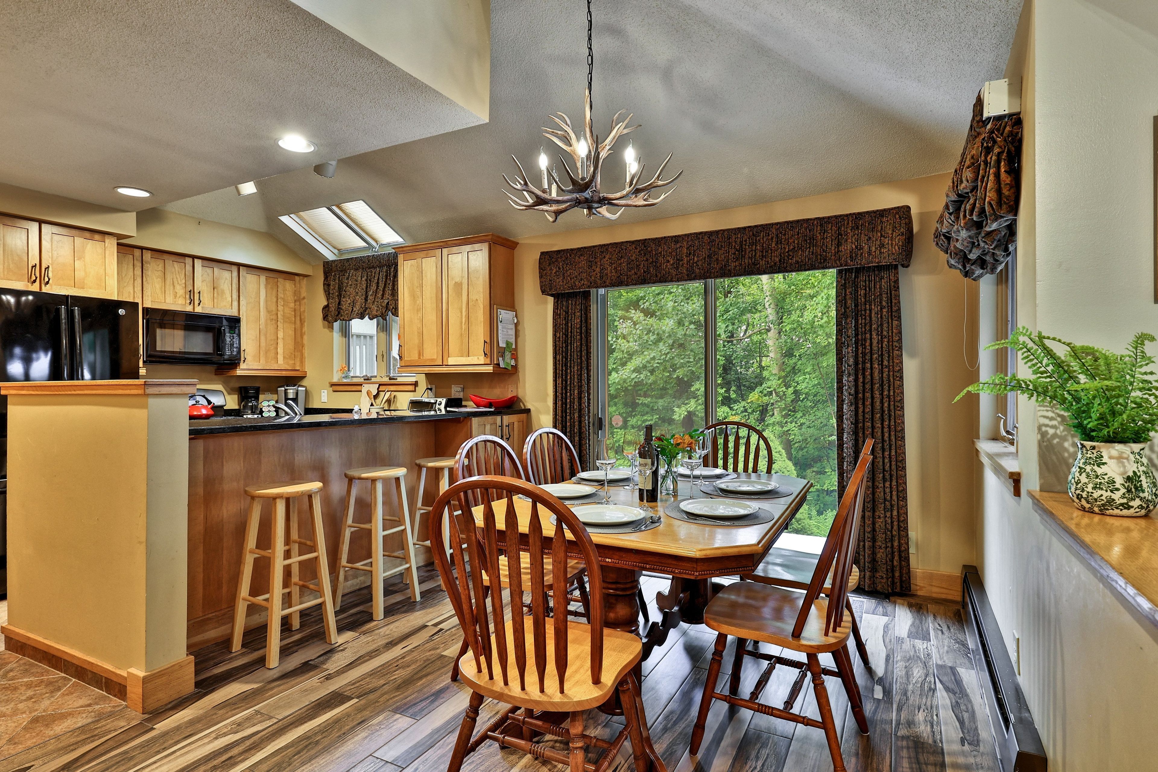 A modern kitchen with wooden cabinets, a black refrigerator, and a dining area with a wooden table and chairs.