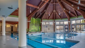 Una piscina interior con techo de madera y amplios ventanales.