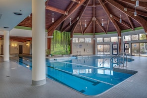 Una piscina interna con soffitto in legno e ampie finestre.