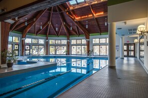 A large indoor swimming pool with a high wooden ceiling and large windows.