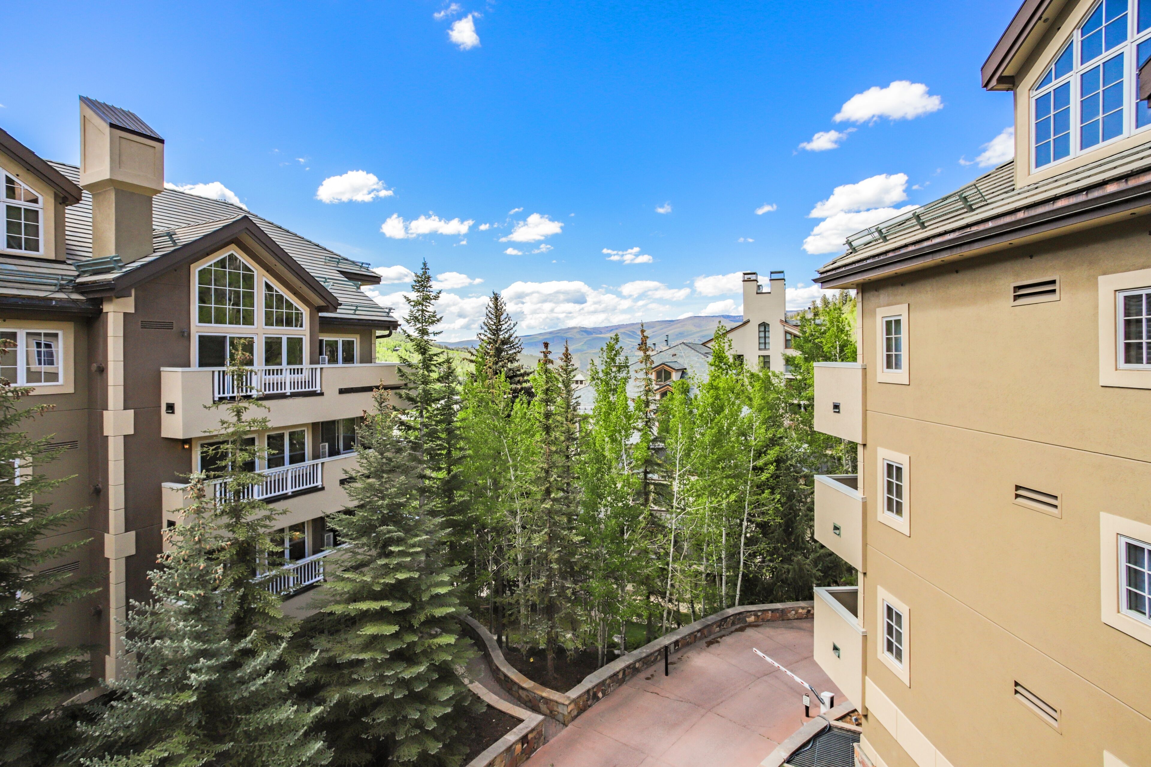 A multi-story building with balconies and a view of mountains.