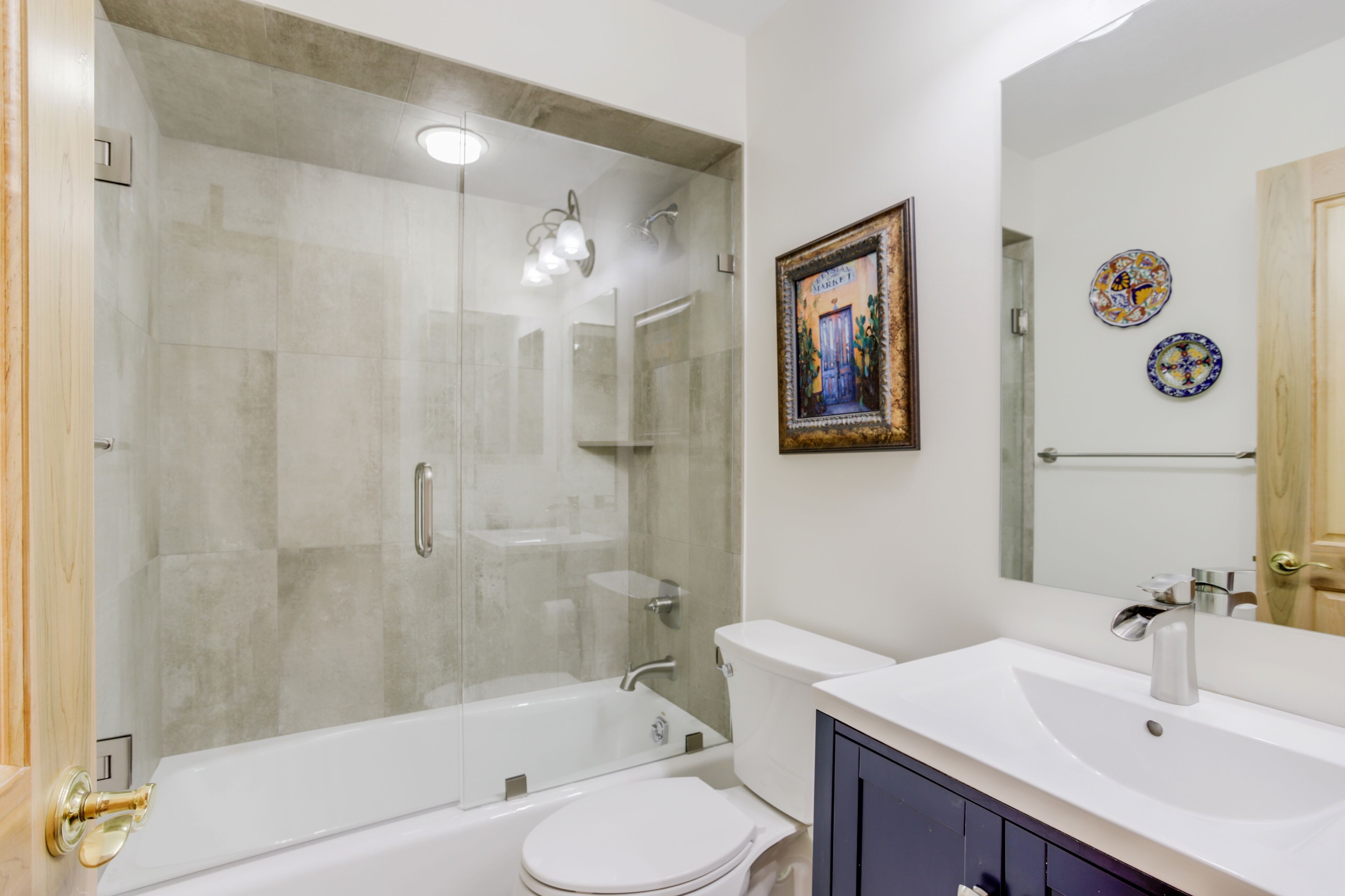 Un bagno moderno con doccia a vetro, vasca da bagno bianca e mobile lavabo con lavandino e specchio.
