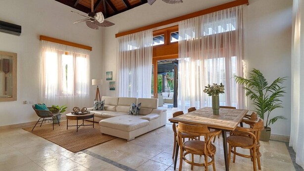 A spacious living room with a high ceiling, a wooden dining table, and comfortable seating. - PERFECT OASIS PRIVATE POOL AND GARDEN PUNTA CANA (Punta Cana)