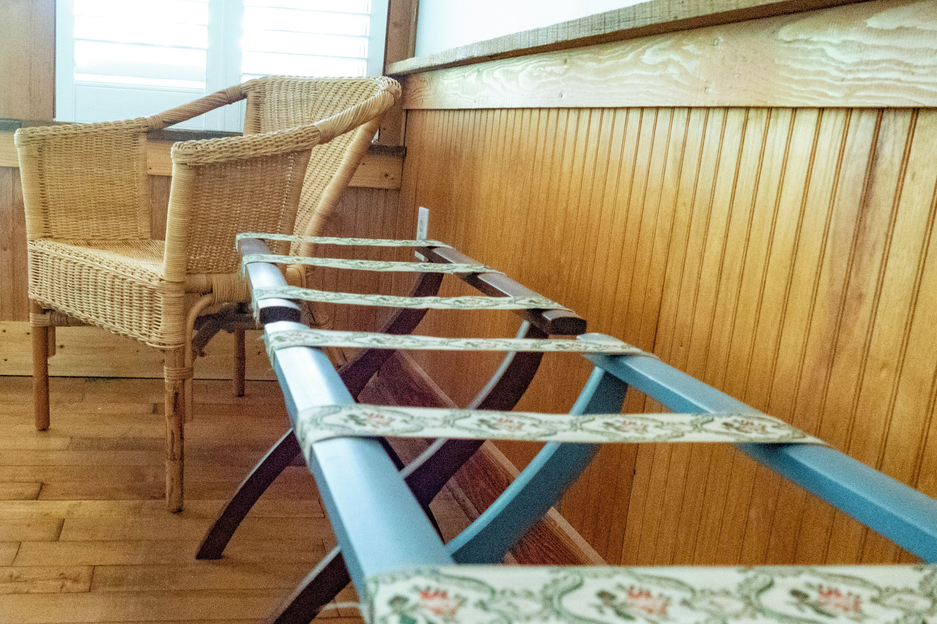 A room with a wooden floor, a wicker chair, and a blue and white striped table.