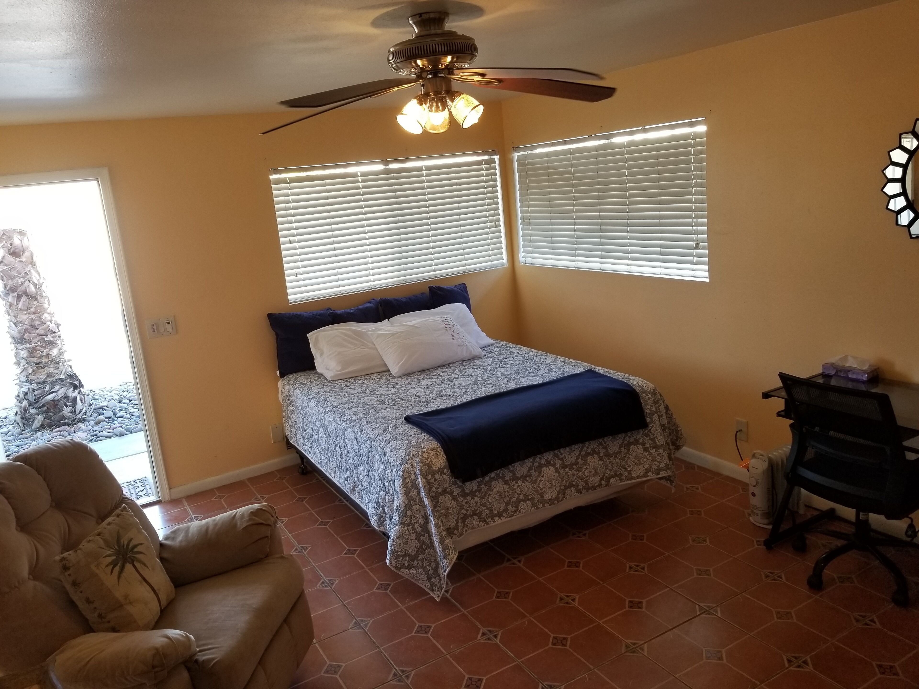 Ein Schlafzimmer mit Bett, Deckenventilator, Schreibtisch und Stuhl.