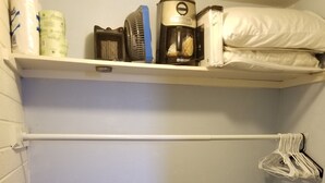 A small storage area with a blue chest of drawers, a white shelf with toiletries, and a blue laundry basket. - Quite studio with RV parking (Lake Havasu City)