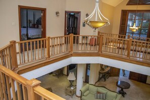 Relax in a spacious living area with a high ceiling, featuring a green sofa, small table, and lamp.