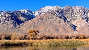 A mountain landscape with a clear sky and a calm body of water reflecting the mountains. - Olancha Lakeside Camping RV Site#2 Near Mt. Whitney (Olancha)