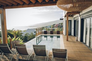 Zona de piscina con sillones de descanso y vista al océano.