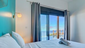 A hotel room with a bed, a view of the ocean, and a balcony with a railing. - Villa Roche Café **** avec piscine / Vue mer panoramique / Saint-Leu Réunion (Saint-Leu)