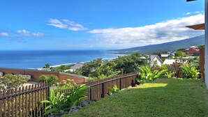 A coastal view with a wooden fence, lush greenery, and a clear blue sky. - Villa Roche Café **** avec piscine / Vue mer panoramique / Saint-Leu Réunion (Saint-Leu)