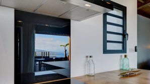A modern kitchen with a wooden countertop, a glass bottle, and a decorative bowl. - Villa Roche Café **** avec piscine / Vue mer panoramique / Saint-Leu Réunion (Saint-Leu)