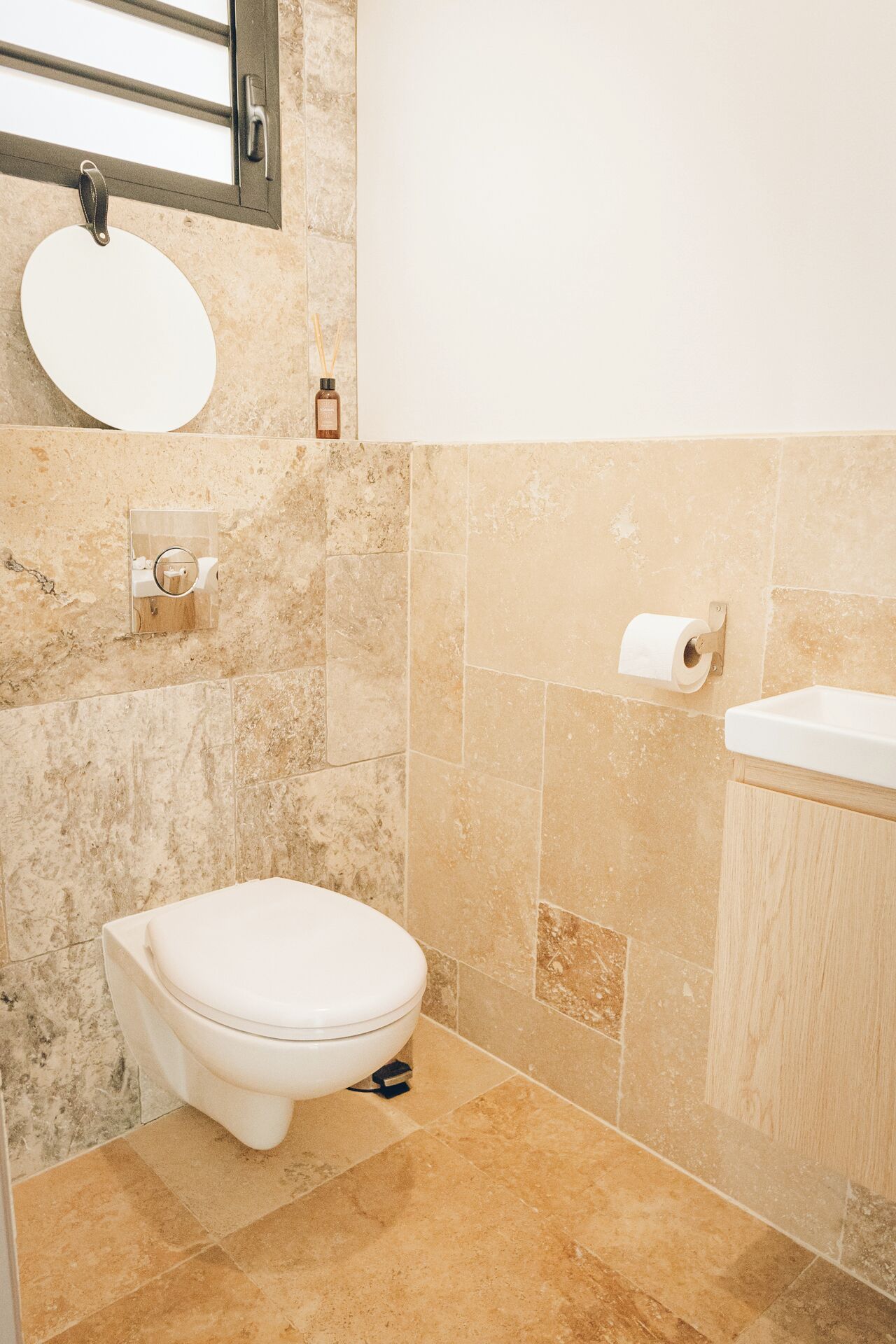 A bathroom with a toilet, sink, and mirror.