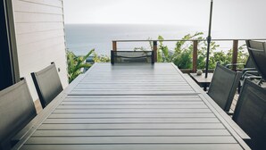A deck with a table and chairs, overlooking the ocean. - Villa Roche Café **** avec piscine / Vue mer panoramique / Saint-Leu Réunion (Saint-Leu)