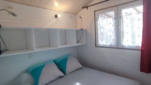 Une chambre à coucher avec un lit, une fenêtre avec des rideaux et une étagère fixée au mur.