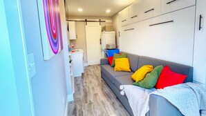 Un soggiorno moderno con un divano grigio, cuscini colorati e una coperta bianca.