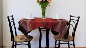 A dining area with a table set for two, featuring a patterned tablecloth, two chairs, and a vase with flowers. - COZY & BEAUTIFUL APART IN SAN BLAS CUSCO (Cusco)