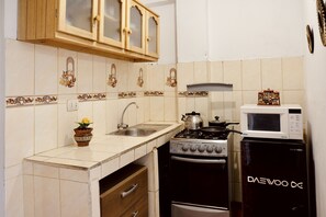 A kitchen with a stove, microwave, sink, and wooden cabinets.