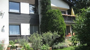 A modern two-story building with a well-maintained garden, potted plants, and a visible balcony with outdoor furniture. - Spacious,comfortable apartment,150m2, first floor,quiet,garden-side with terrace (Wien)