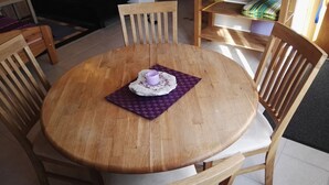 Ein runder Holztisch mit einer violetten Tischmatte und einem weißen Tuch mit einer violetten Tasse.