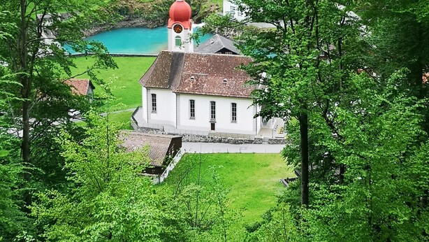 Eine Kirche mit einer roten Kuppel, umgeben von üppigen grünen Feldern und Bäumen.