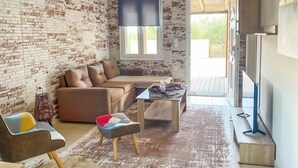 Ein Wohnzimmer mit Backsteinwand, einer Couch, einem Couchtisch und einem Fernseher.