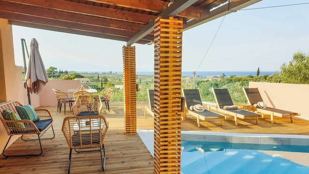 Eine Holzterrasse mit Liegestühlen und einem Pool.