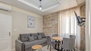 A modern living room with a grey sofa, a round wooden table, and grey chairs. - InMotion Luxury Rooms (Split)