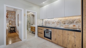 A modern kitchen with a stone backsplash, wooden cabinets, and a built-in oven. - InMotion Luxury Rooms (Split)