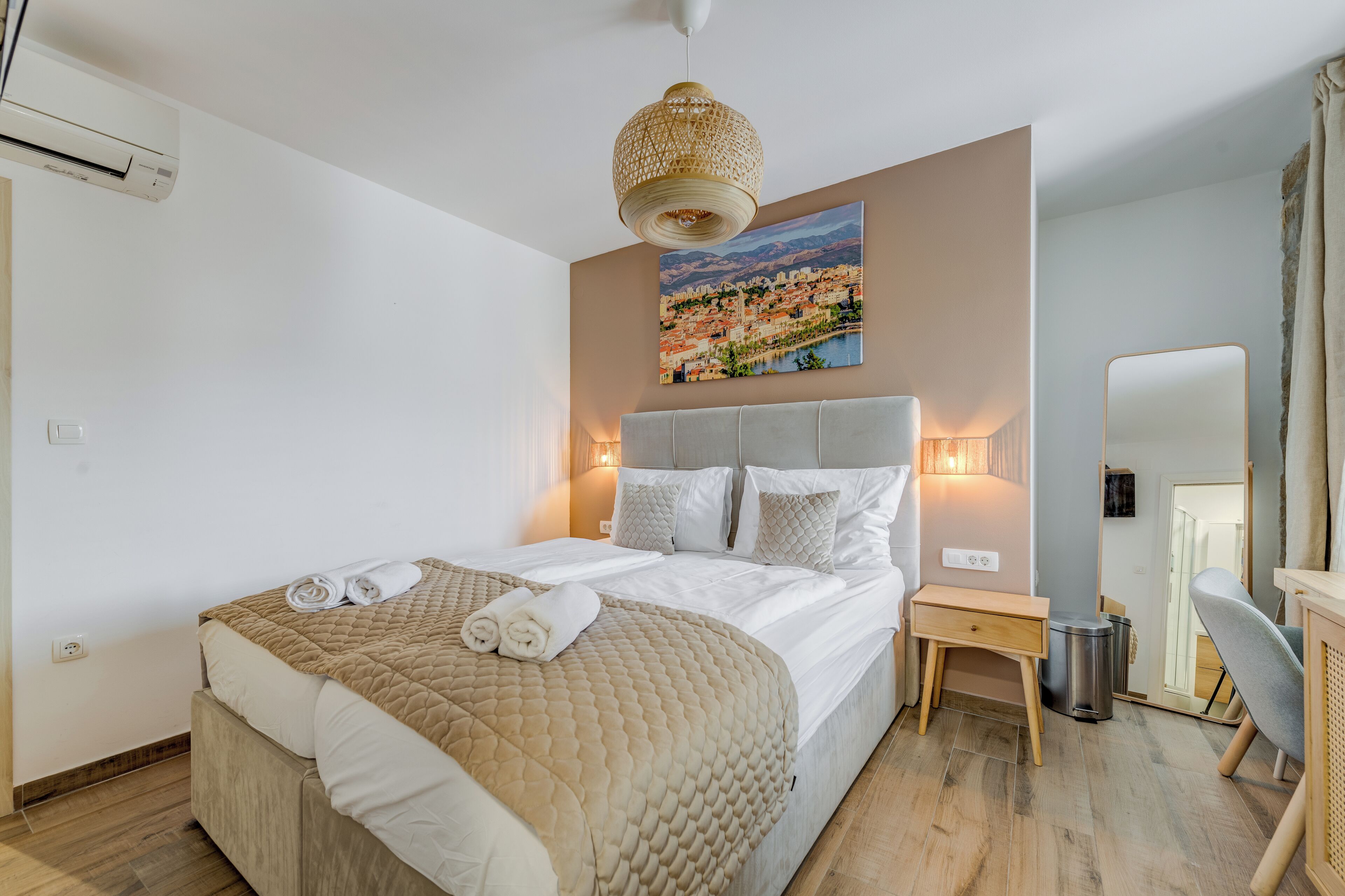 A neatly made bed with a beige quilt, a bedside lamp, and a small wooden nightstand.