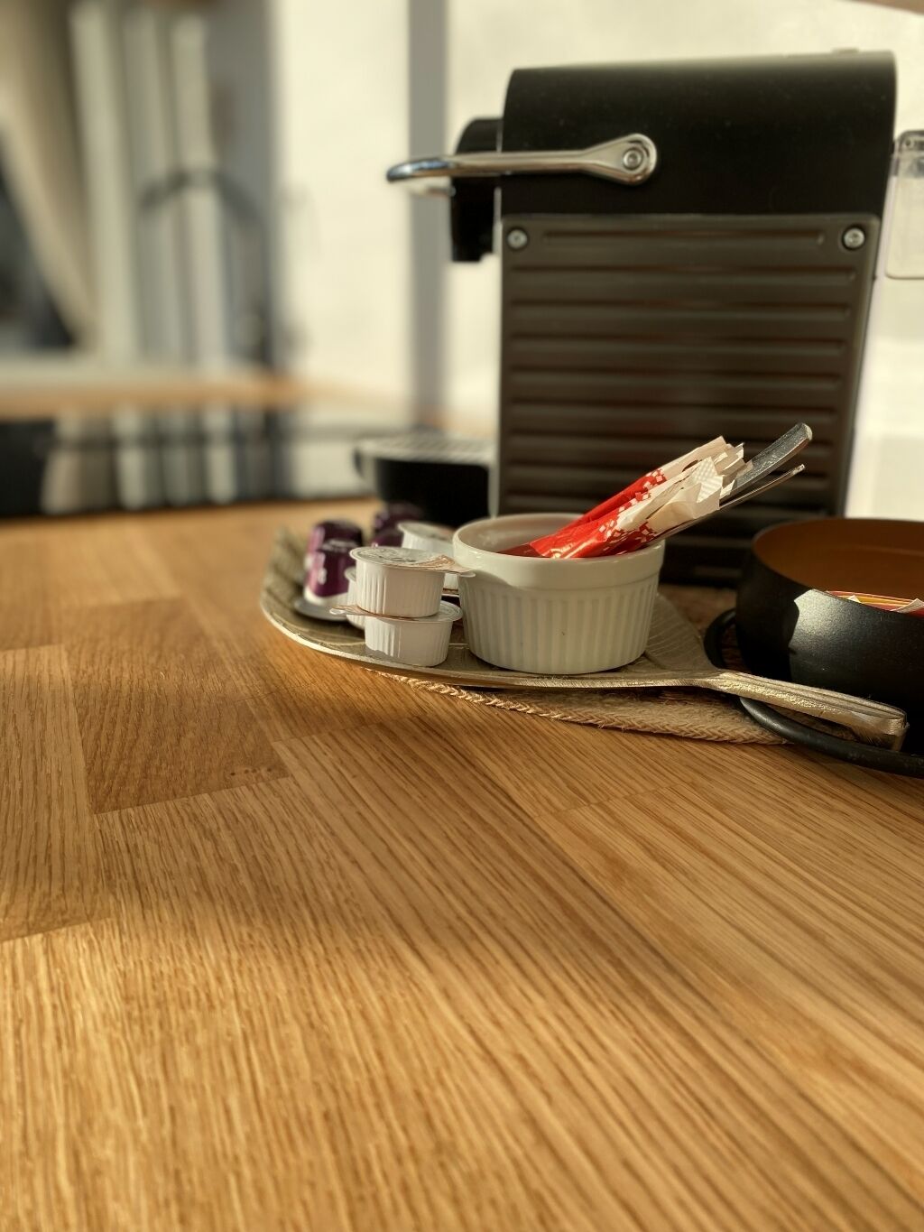 A wooden table with a tray holding small white containers, a black object, and a red item.