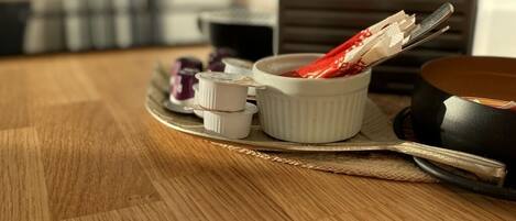 A wooden table with a tray holding small white containers, a black object, and a red item.