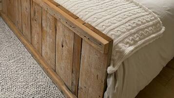 Una camera da letto con un letto con struttura in legno, una coperta bianca e cuscini decorati.