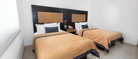 Habitación de hotel con dos camas, una mesita de noche con lámpara y un equipo de aire acondicionado en la pared.
