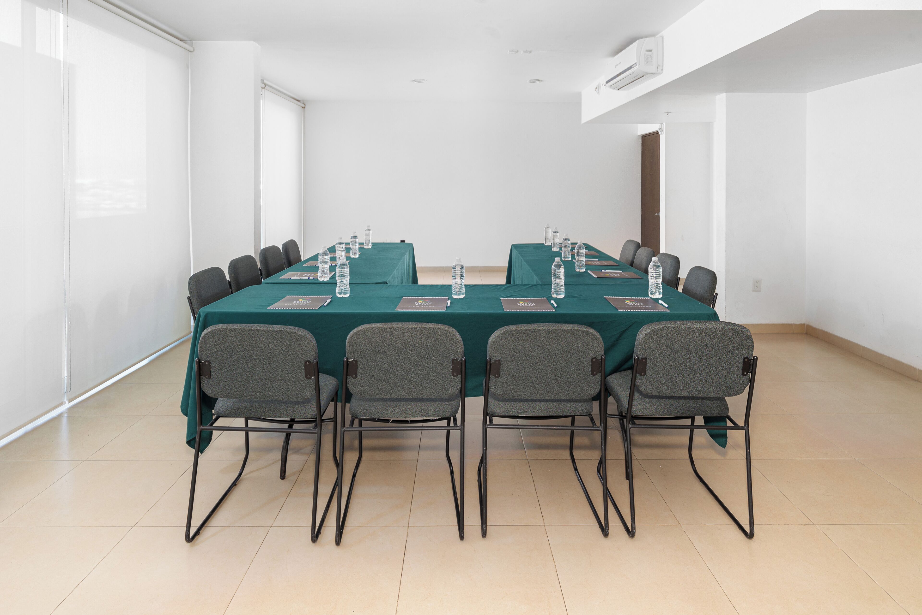 Un salón de conferencias con una larga mesa, sillas, botellas de agua y placas de identificación.
