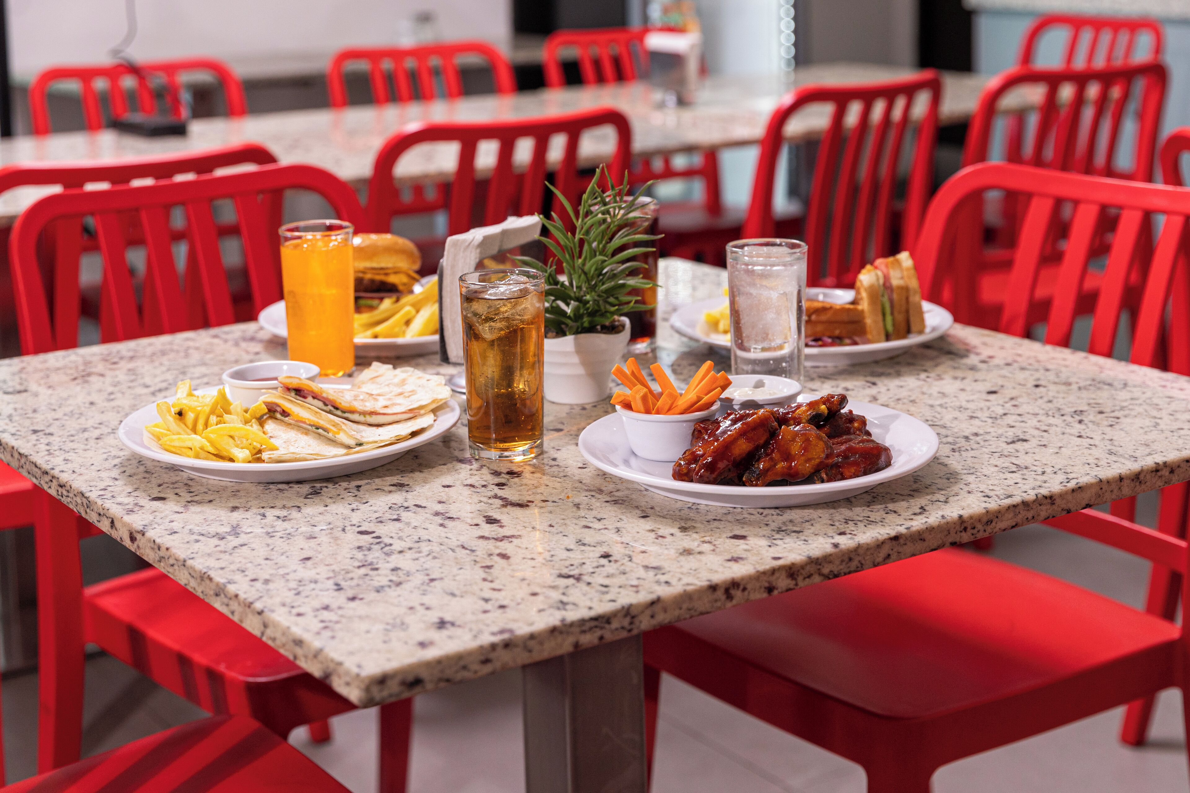 A dining table with plates of food, a glass of iced tea, and a potted plant.