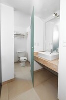 A bathroom with a white toilet, a sink with a mirror, and a towel rack.