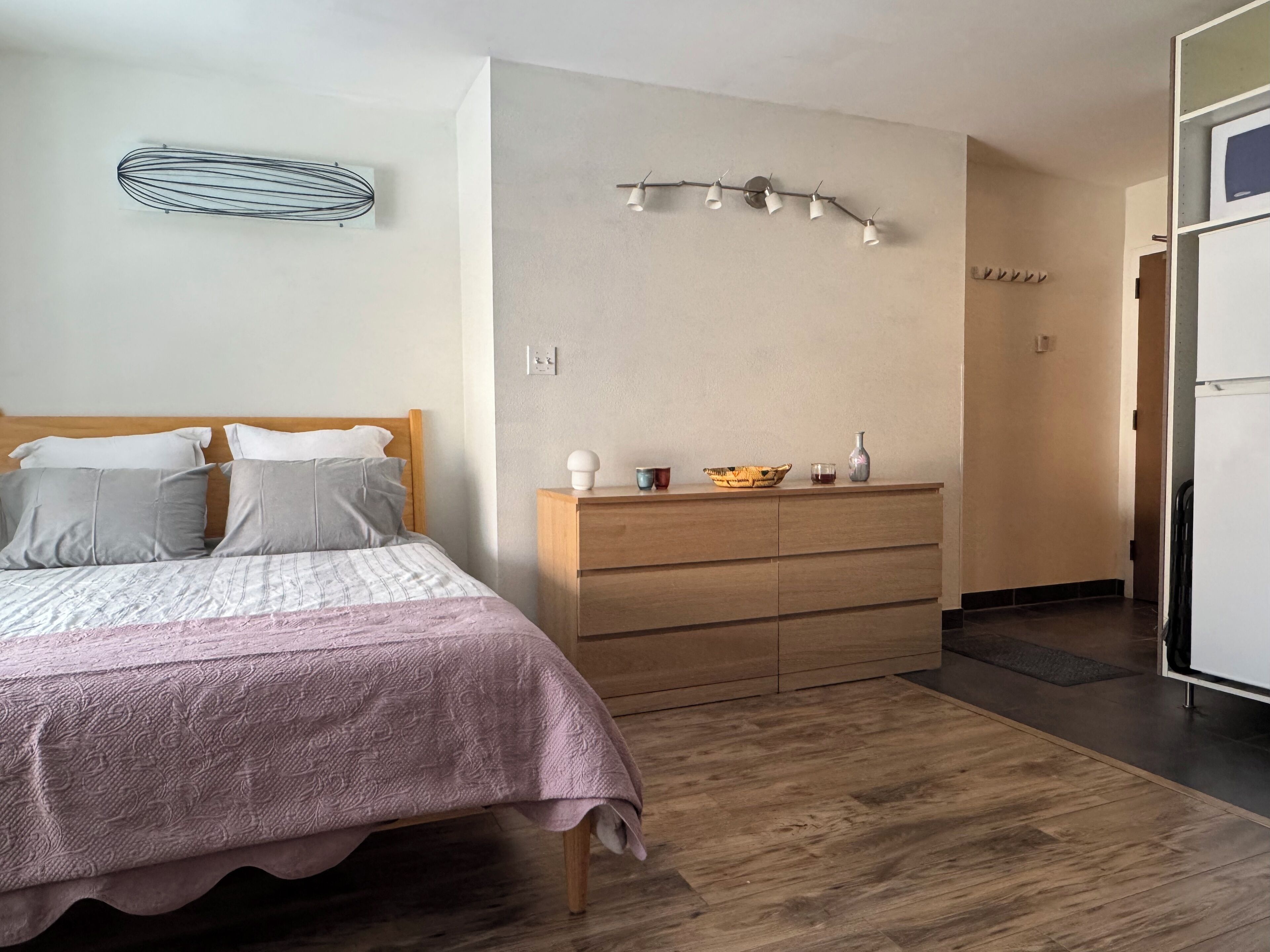 Una camera da letto con un letto, una cassettiera in legno e una lampada a parete.