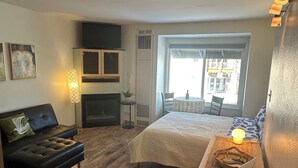 Une chambre moderne avec un lit, un canapé, une petite table avec une lampe et une fenêtre donnant sur un beau paysage.