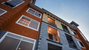 A multi-story building with a brick facade, large windows, and balconies. - Shilo Space-Emerald Apt.Free WiFi & Modern Look. (Kampala)