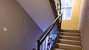 A staircase with a black metal railing, beige steps, and a window at the top. - Shilo Space-Emerald Apt.Free WiFi & Modern Look. (Kampala)