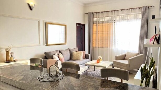 A modern living room with a marble island, a sofa set, a coffee table, and a dining table. - Shilo Space-Emerald Apt.Free WiFi & Modern Look. (Kampala)