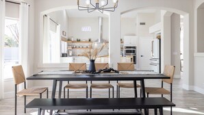 A modern dining room with a black table, woven chairs, and a central vase. - Fun Filled Stadium Getaway w/ Heated Pool & Golf (Glendale)