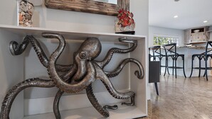 Una cocina moderna con una escultura decorativa de pulpo en la pared, un mueble de madera y una zona de bar con taburetes.