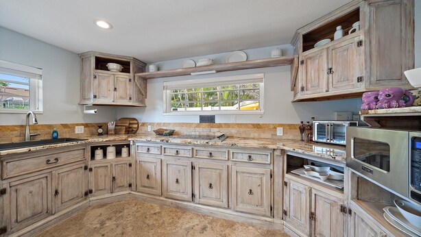 Una cocina con armarios de madera, horno empotrado y ventana con vistas al verdor.