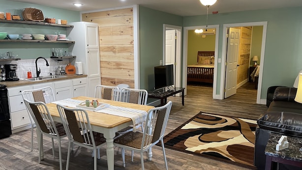 A modern kitchen with white cabinets, a dining table with chairs, and a living area with a sofa and a TV. - New Near Jamestown Dock - A (Jamestown)